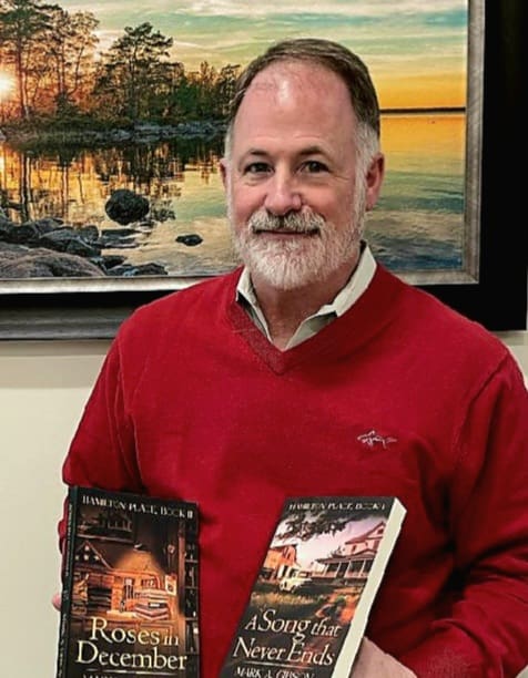 A man in red shirt holding two books.