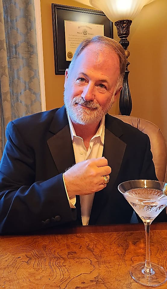 A man sitting at a table with a martini glass.